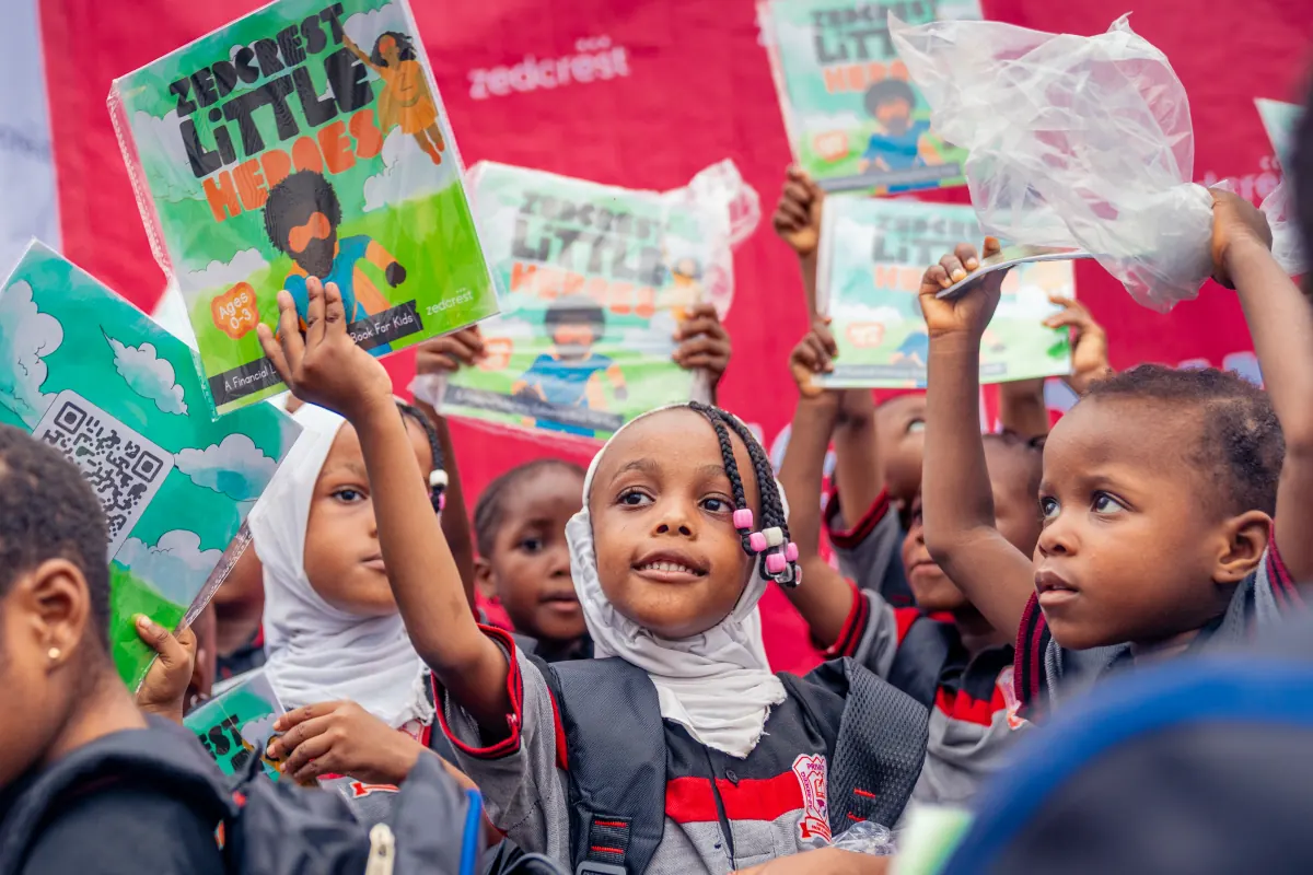 Children raising their Little Heroes books during an outreach session